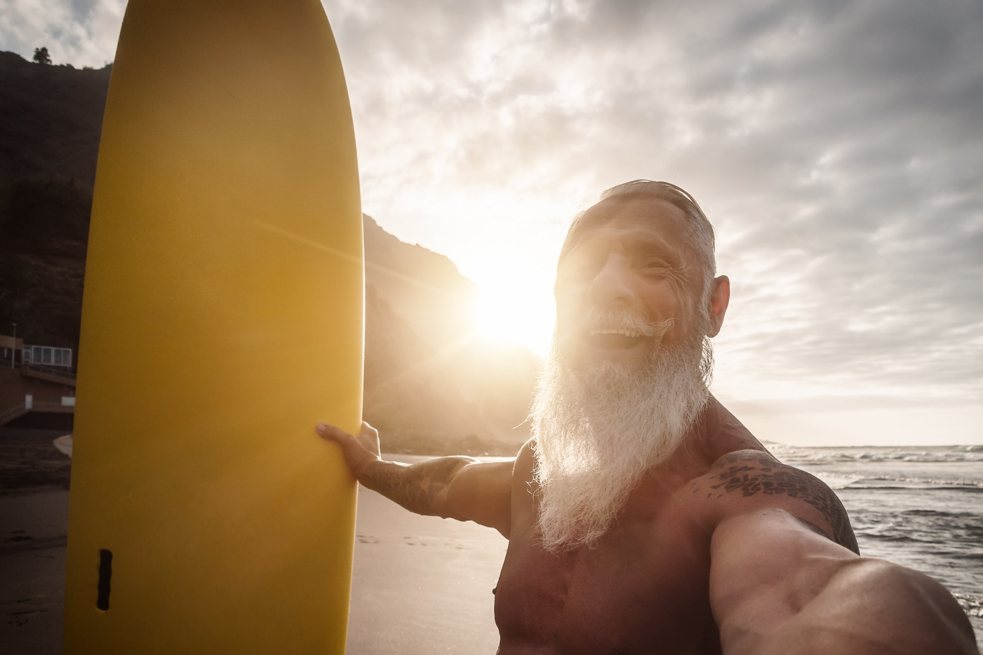 Glücklicher Rentner hat Spaß beim Surfen im Sonnenuntergang