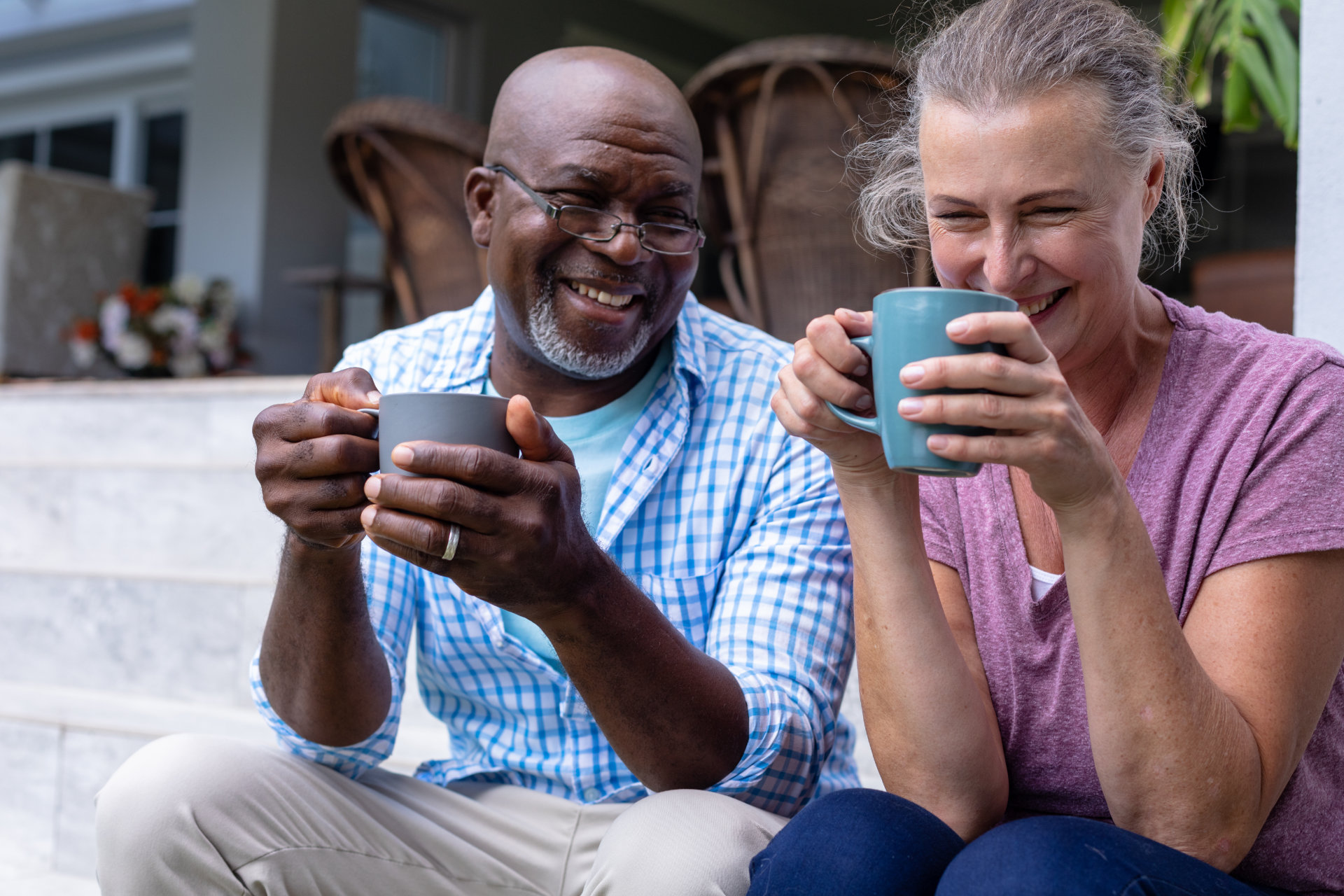 Glückliches älteres Paar, das gemeinsam Kaffee trinkt, während es auf der Treppe sitzt