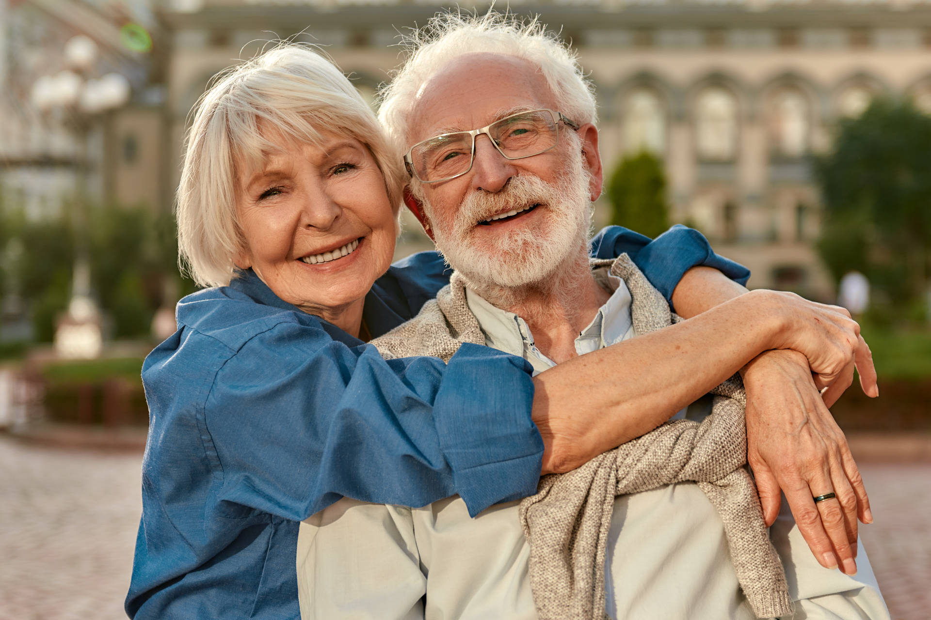 fröhliches Seniorenpaar in Freizeitkleidung das sich umarmt-min